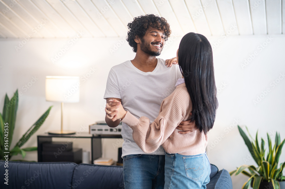 Fototapeta premium A young couple smiling and dancing in the room