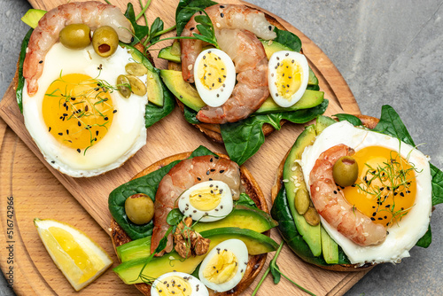 Toast with wholemeal bread, soft fried egg, spinach, avocado, shrimps on wtite background, Ketogenic breakfast. superfood concept. Healthy, clean eating. Top view
