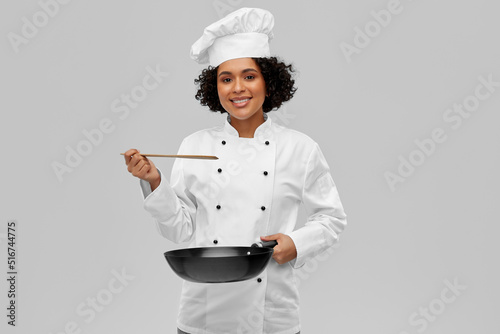 food cooking, culinary and people concept - happy smiling female chef with frying pan over grey background