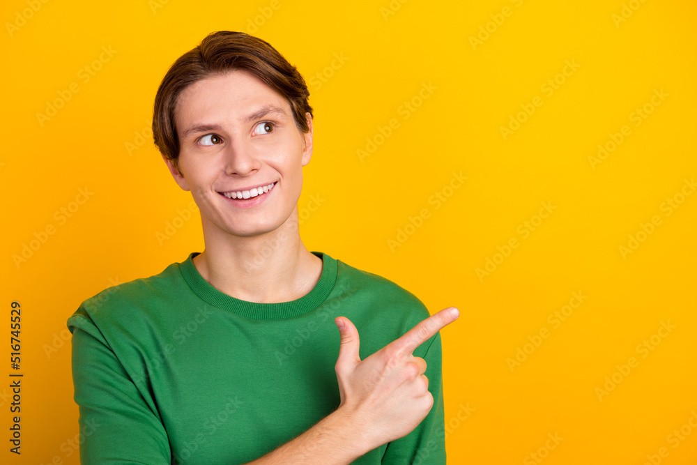 Handsome smiling man pointing away yellow color background advertising discounts promo isolated Handsome smiling man pointing away yellow color background advertising discounts promo isolated