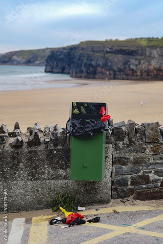 garbage bin overflowing with bags of dog facies at the beach.