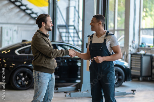 Joyful mechanic greeting his customer at the service station