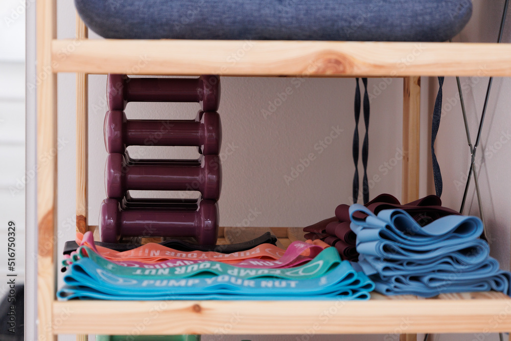 Sports equipment of weights and dumbbells laying on wooden shelf. 1.5 kg, 2 kg. Different colors weights for hands. Sports equipment of weights and dumbbells laying on wooden shelf. 1.5 kg, 2 kg. Different colors weights for hands.