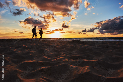Tourists walk on the beach during sunset over the Baltic Sea