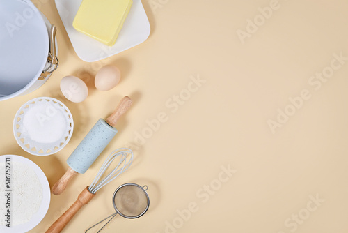 Cake dough ingredients and baking tools on beige background with copy space