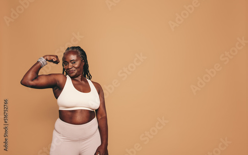 Photo Mature woman flexing her bicep in a studio
