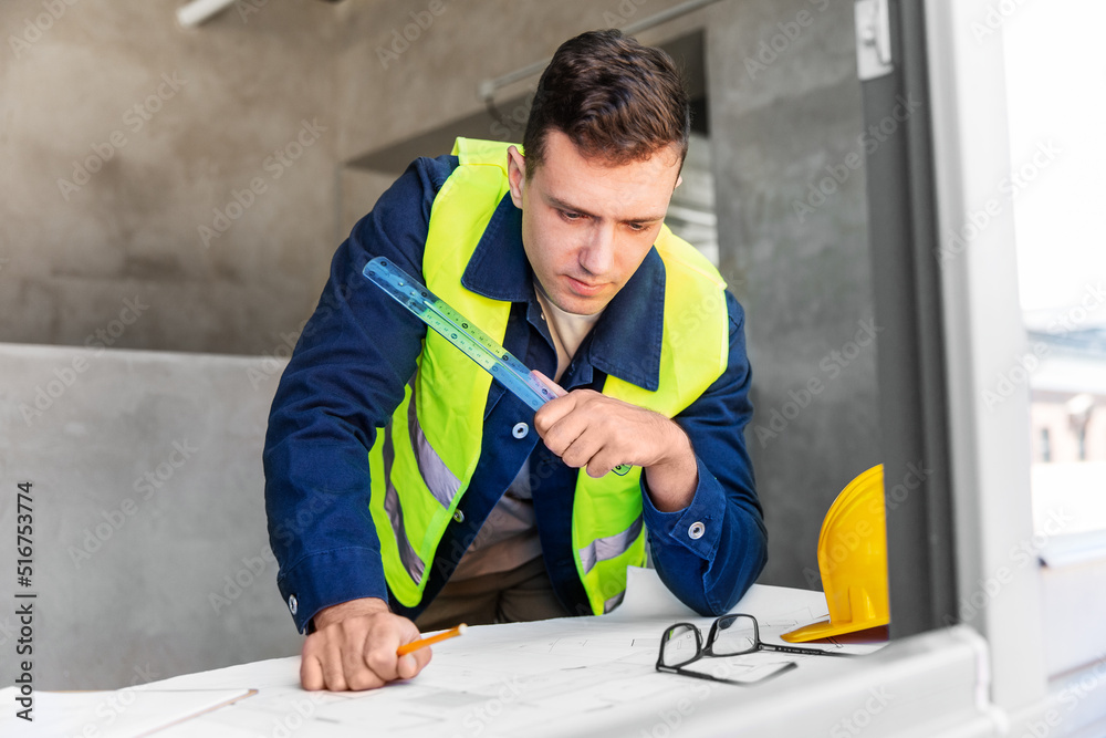 architecture, construction business and people concept - male architect with blueprint and ruler working at office architecture, construction business and people concept - male architect with blueprint and ruler working at office