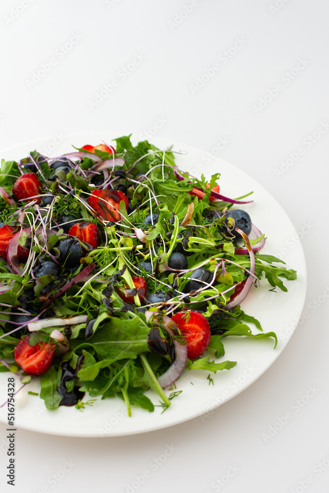 Light salad with arugula and berries, strawberries and blueberries, delicious healthy summer salad on a white background Light salad with arugula and berries, strawberries and blueberries, delicious healthy summer salad on a white background