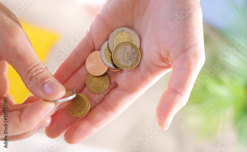 Hands hold euro coins of different denominations. State aid in times of crisis to compensate for inflation. Salary increase and basic social security. Inflation, purchasing power and social crisis.