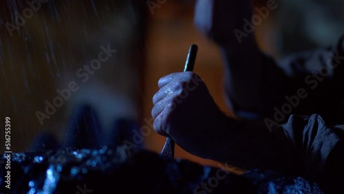 
Rain starting while the sculptor is shaping a rock at night