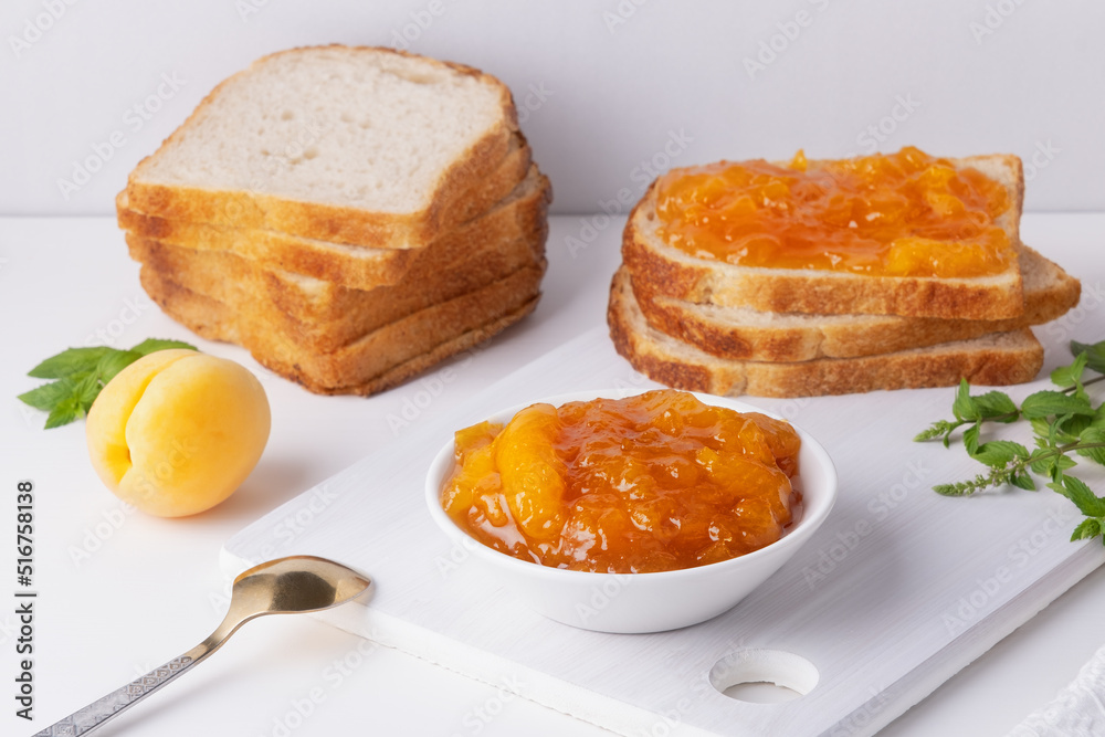Toasts of bread with apricot jam and fresh fruits with mint on white wooden table. Tasty breakfast Toasts of bread with apricot jam and fresh fruits with mint on white wooden table. Tasty breakfast