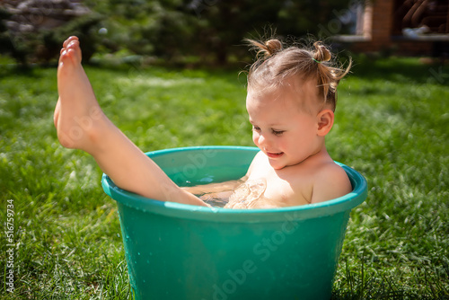 Baby girl flop in a basin with water on home backyard in summer time