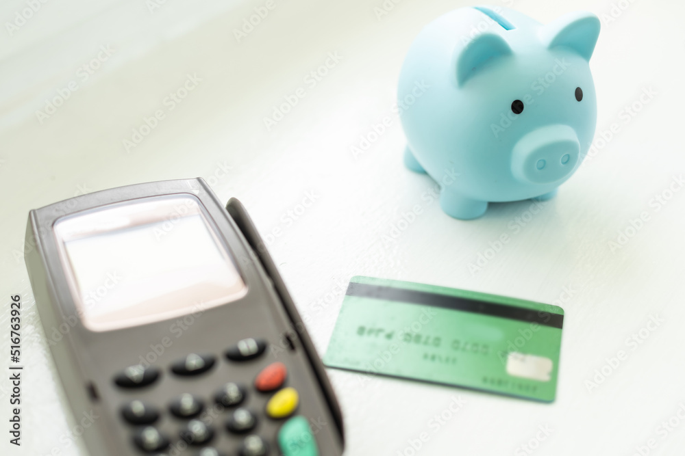 money and savings coins with dollar bills and a payment terminal for cashless payments with a pink piggy bank for savings. money and savings coins with dollar bills and a payment terminal for cashless payments with a pink piggy bank for savings.