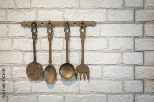 Set of antique style kitchen untensils which are handing on white brick wall, Interior decoration object photo. Selective focus. photo