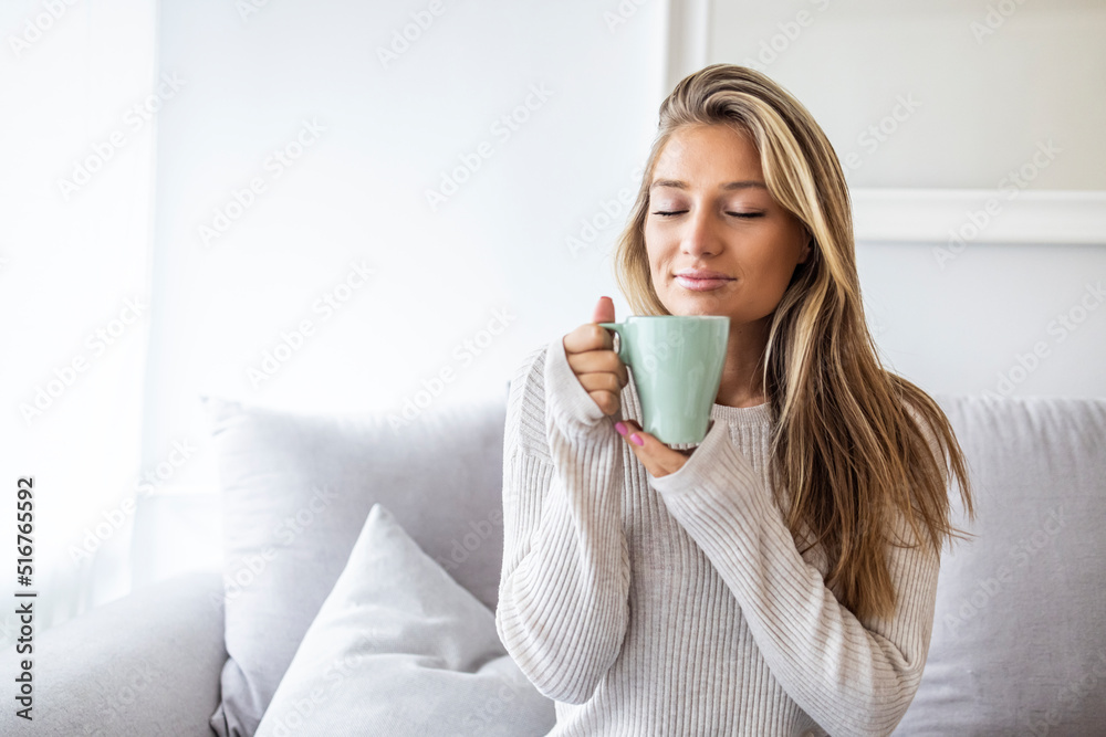 Portrait of joyful young woman enjoying a cup of coffee at home. Smiling pretty girl drinking hot tea in winter. Excited woman wearing sweater and laughing in an autumn day. Portrait of joyful young woman enjoying a cup of coffee at home. Smiling pretty girl drinking hot tea in winter. Excited woman wearing sweater and laughing in an autumn day.
