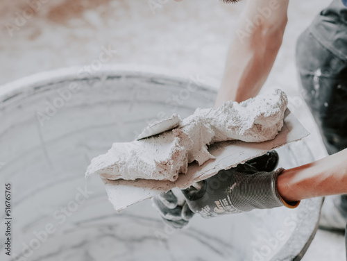 Fotografi The hands of a Caucasian male plasterer i apply fresh putty with one spatula to