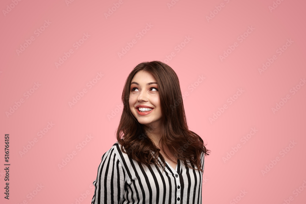 Optimistic young woman smiling and looking up in pink studio Optimistic young woman smiling and looking up in pink studio