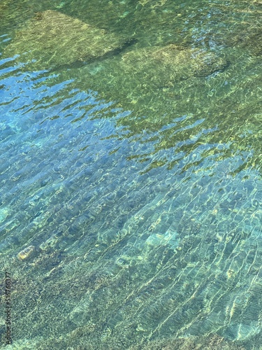 Sea water green glittering surface. Transparent sea water with pebbles and stones on the bottom. Summer  zen  harmony  relax  vacation.