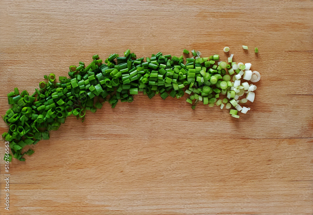 Chopped fresh green onions on a wooden board, top view. Chopped fresh green onions on a wooden board, top view.