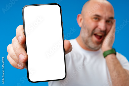 Middle-aged man showing blank smartphone screen with copy space against blue background