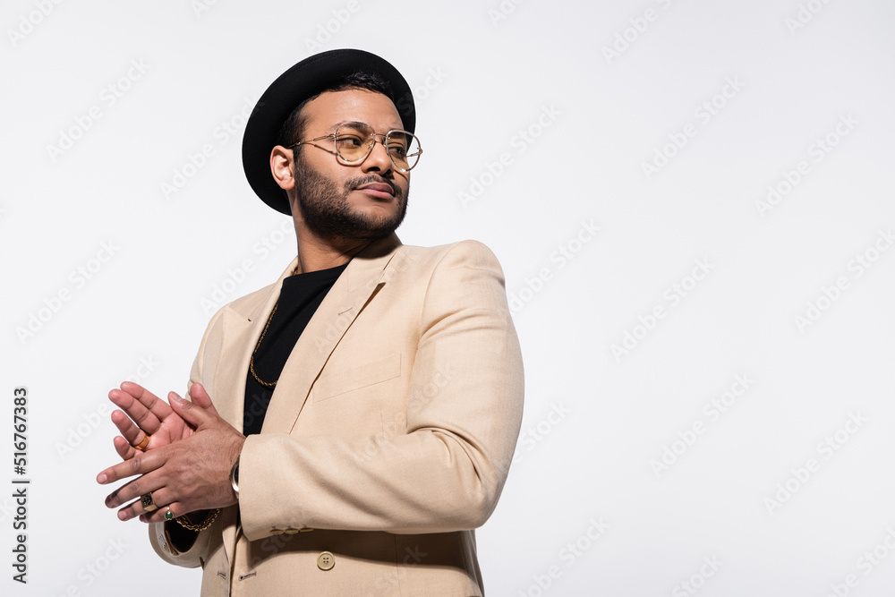 indian hip hop performer in fedora hat and eyeglasses looking away isolated on grey. indian hip hop performer in fedora hat and eyeglasses looking away isolated on grey.