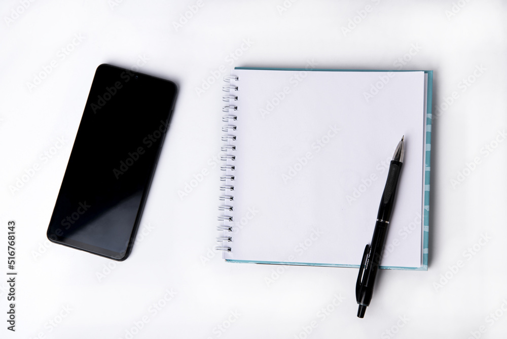 Notepad, blank sheet and phone on a white background. Top view. Notepad, blank sheet and phone on a white background. Top view.