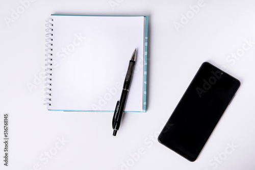 Notepad, blank sheet and phone on a white background. Top view.