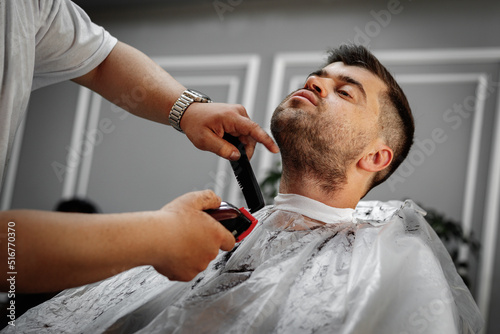 Male client getting haircut by hairdresser in barbershop