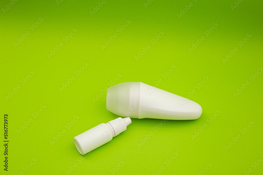 White deodorant and white bottle on a bright green background White deodorant and white bottle on a bright green background