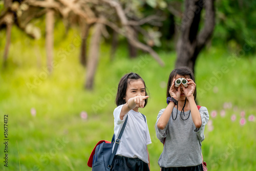 Children travel in flower field and holding binoculars on green nature background