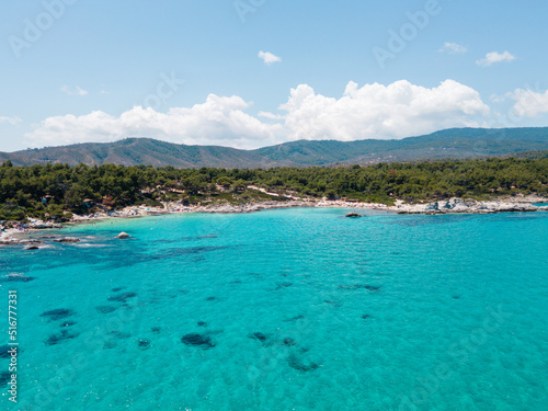 Aerial view of scenic and clear turquoise sea water from above  with white rocks and green trees around,  Mediterranean travel concept, Portokali beach in Sithonia, Greece  © Miro Nenchev