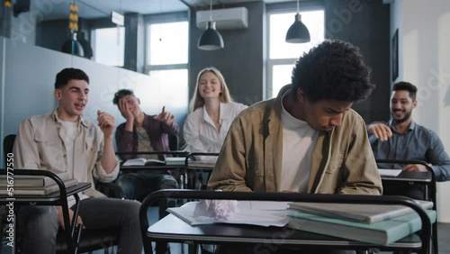 Unhappy african american student loser feeling mocking bullying anger from classmates suffering from abuse young upset distressed guy sits alone in classroom at desk discrimination and racism concept
