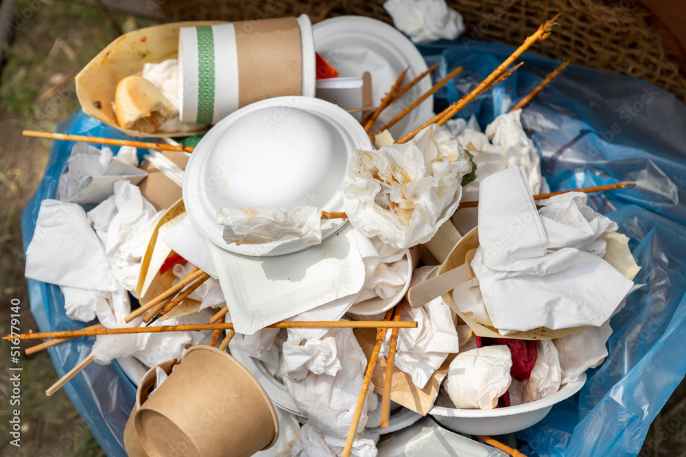 Closeup view of full garbage bin can with used dirty paper cardboard