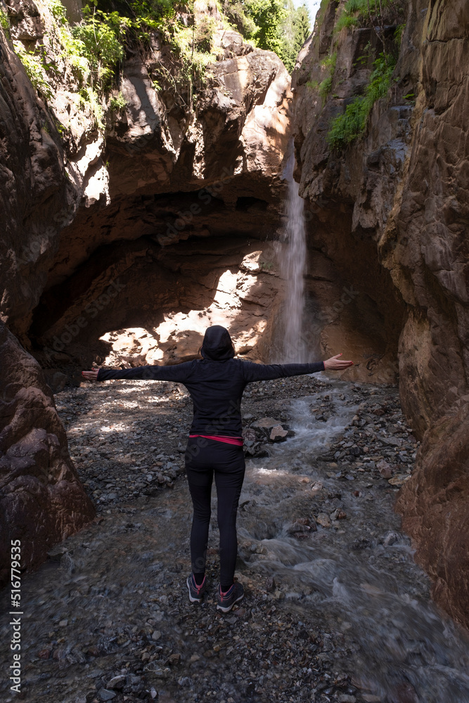 person with open arms in the cascade of barezze in Trentino Alto Adige