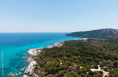 Aerial view of scenic and clear turquoise sea water from above  with white rocks and green trees around,  Mediterranean travel concept, Portokali beach in Sithonia, Greece  photo