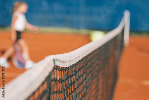 Sports background with copy space. Tennis net with blurred player on background.  © Nina