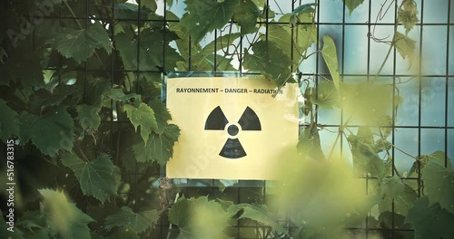 Plant Vegetation Covering Nuclear Radiation Danger Sign on Overgrown Fence with Contaminated Airborne Radioactive Particles in Slow Motion 4K photo