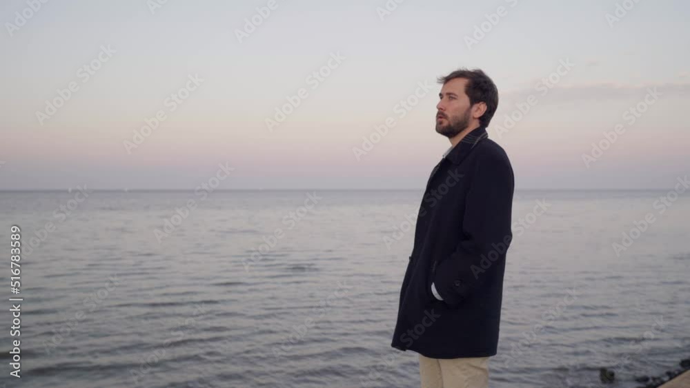 young man with overcoat looks at the horizon at sunset next to the river young man with overcoat looks at the horizon at sunset next to the river