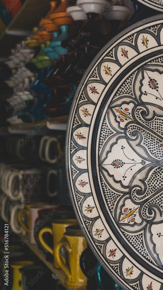Ceramic plate with beautiful ornamentation and colorful details in the foreground and lots of ceramic bowls behind