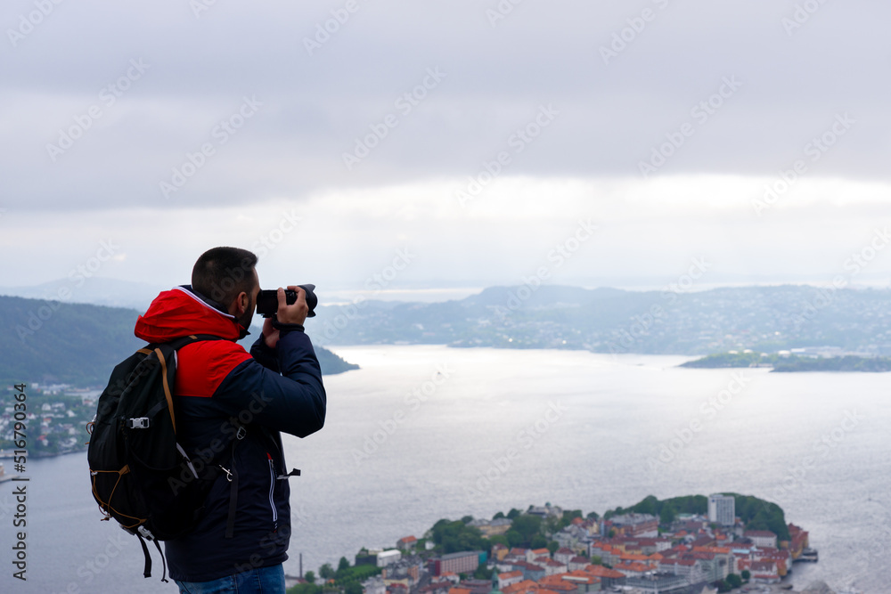 Unrecognizable photographer with his backpack on his back and photographing the city of Bergen and the fjord in Norway.