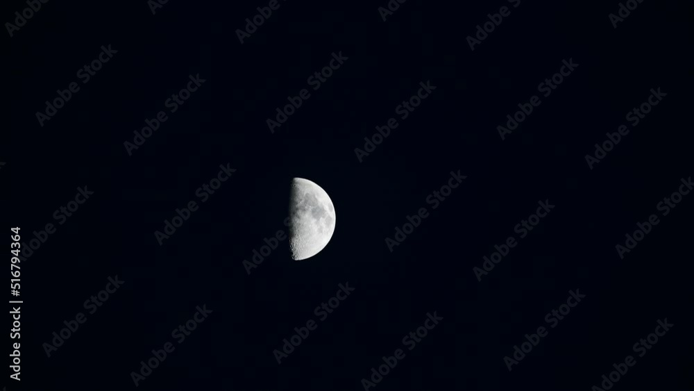 Bright half moon at night moving slowly in the sky with copy space Bright half moon at night moving slowly in the sky with copy space