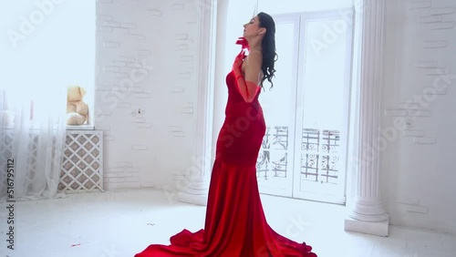 Slow Motion tractive woman in red dress in the spacey room near the window.