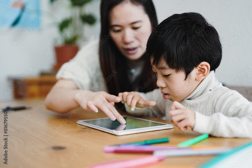 Asian mother and child learning with digital tablet indoor - Daycare and technology concept Asian mother and child learning with digital tablet indoor - Daycare and technology concept