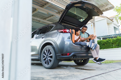 Cheerful Black African American Father and Son playing sitting in car trunk before Road Trip on vacation