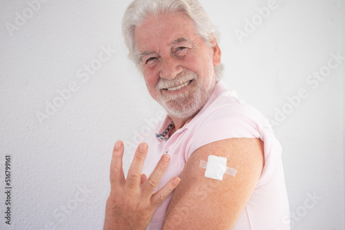 Old senior Caucasian smiling man after receiving the fourth booster dose of the covid 19 coronavirus vaccine. Concept of protection, responsibility and healthcare