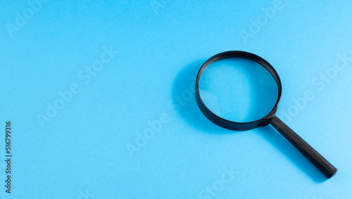 Searching for informational data on the Internet. Information search concept. Magnifying glass on a blue background. View from above. Copy space. Place for text.