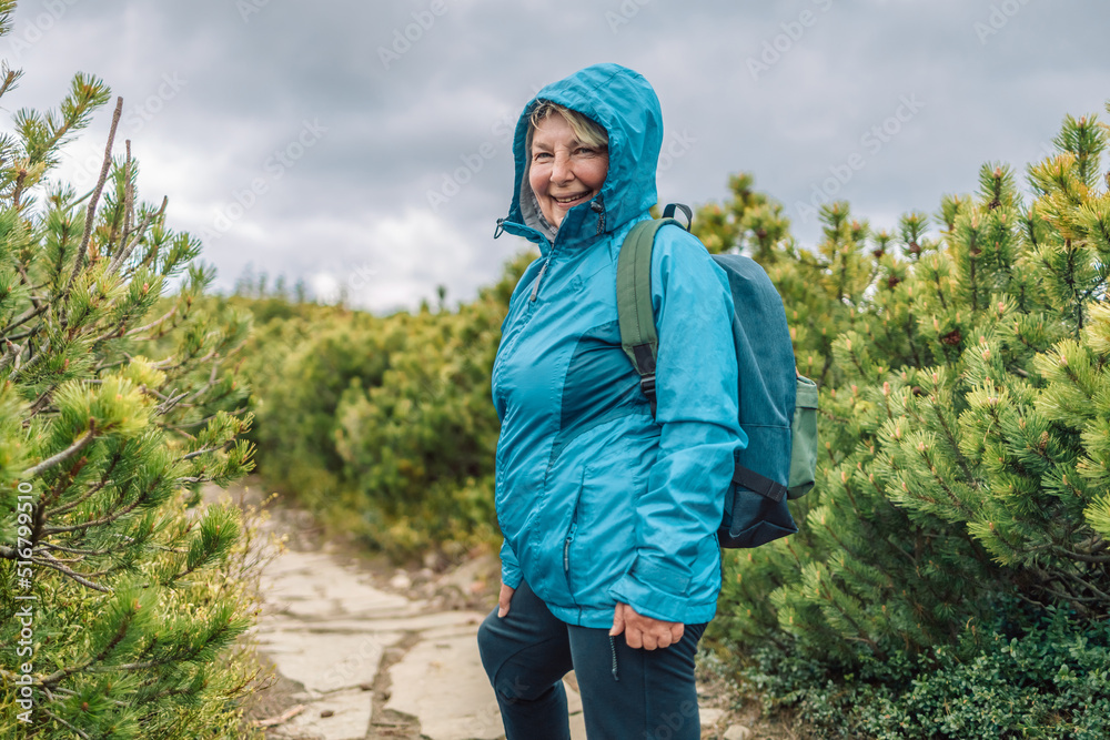 Happy 50s woman traveler in sport clothes going mountains landscape on background. Travel Lifestyle concept. Adventure summer vacations Happy 50s woman traveler in sport clothes going mountains landscape on background. Travel Lifestyle concept. Adventure summer vacations