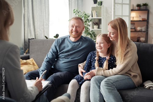 Fotografija Happy parents with child talking to social worker during meeting at home after t