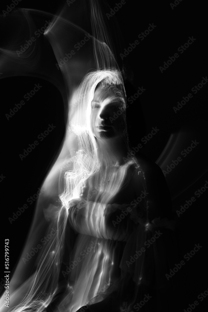 Abstract human silhouette in light trails of light painting with white light beams. Portrait in the style of light painting. Long exposure photo. Image contains noise and motion blur
