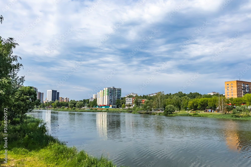 Pushkino, Russia, July 10, 2022. Multi-storey residential buildings and old park on the banks of the Serebryanka river